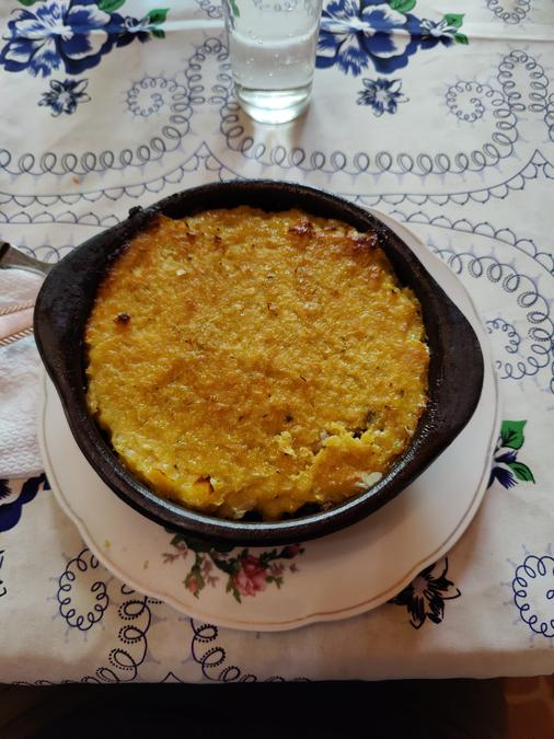 Chilean dish pastel de choclo in a clay bowl set on a table.