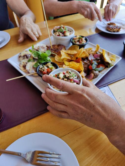 Man holding a dish of salsa in front of an appetizer share plate.