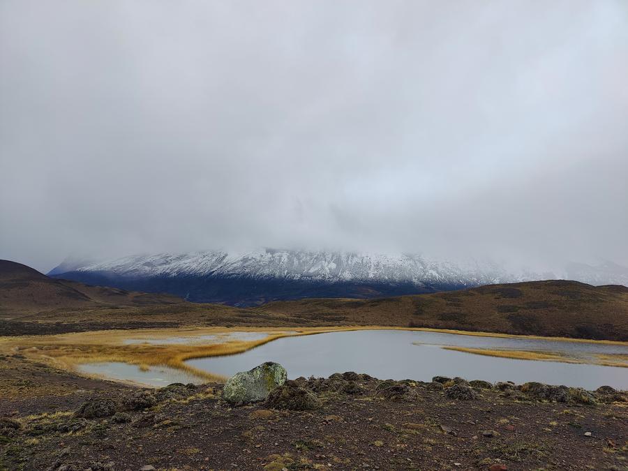 A mountain lake in front of a chain of snow capped mountains.